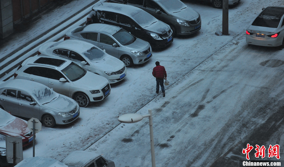 11月18日，行人在沈陽街頭的積雪中穿行。