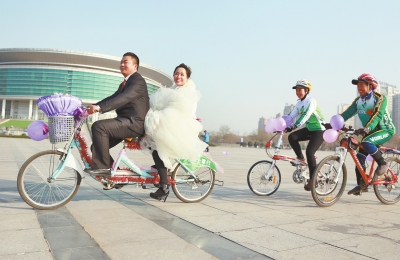 氣球和鮮花裝點(diǎn)的雙人自行車，新郎郝幸福載著美麗新娘回家。