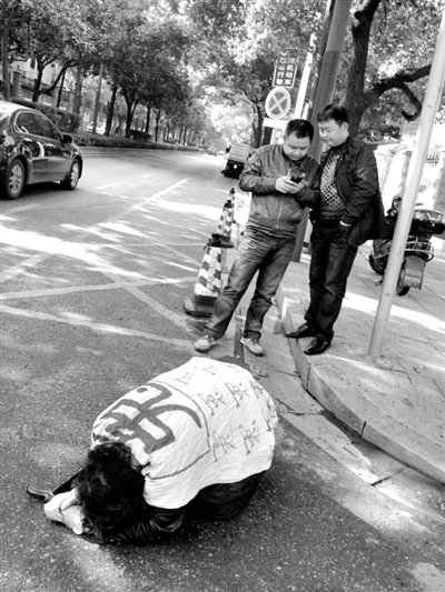 兩名接訪人員與患有癌癥的訪民段新德合影時(shí)，在拍照時(shí)查看手機(jī)。