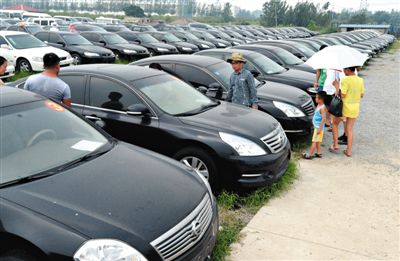 昨日，市民在山東棗莊一家拍賣公司場地上查看待拍賣公車。當(dāng)日，棗莊市103輛公車公開拍賣。新華社記者