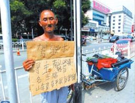 老人舉著牌子在路邊等候失主。京華時(shí)報(bào)記者譚青攝