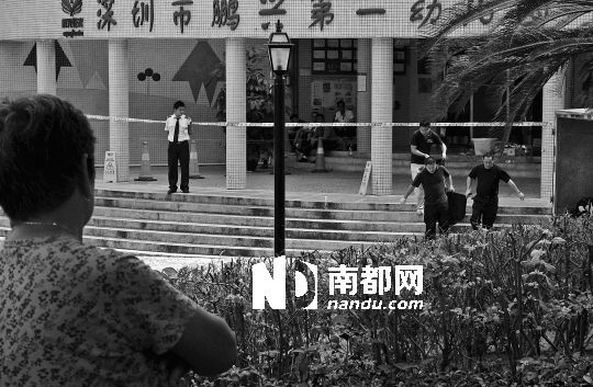 →7月19日，鵬興花園第一幼兒園門前，民警在現(xiàn)場進行完勘查取證后，園長和保安的尸體被運走。南都記者 徐文閣 攝