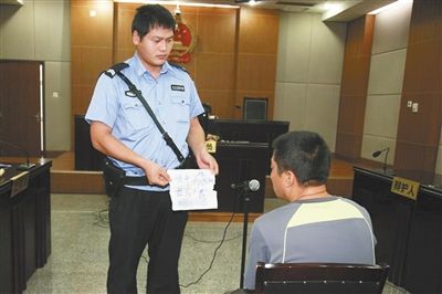 昨日庭審中，法警向趙某出示其扎完車胎后所留辱罵公司的紙條。通訊員 李秀文 攝
