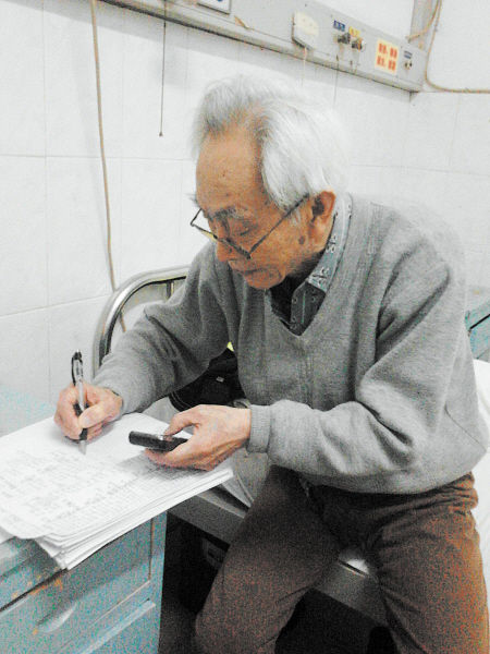 杜修源老人埋頭寫著特殊的“日記”。 李卓 攝