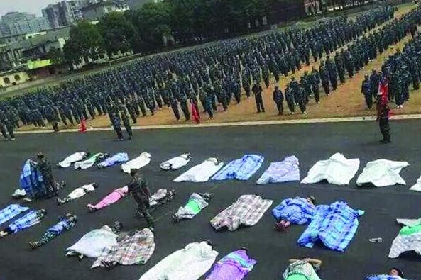 20多名女生躺在瀝青跑道上，身上嚴嚴實實地裹著棉被，接受太陽的照曬。