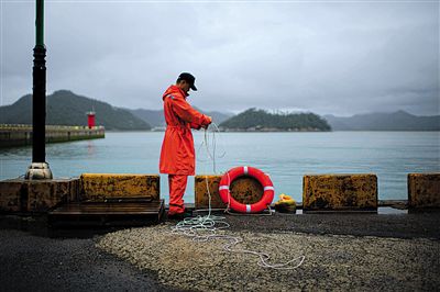 7月6日，韓國珍島，一名海岸警察在港口系救生圈。4月，客輪在珍島近海發(fā)生沉船事故后，仍有11人下落不明。