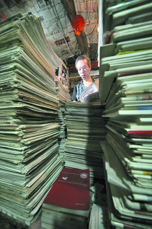 王曉民坐在寫字桌前，被報(bào)紙淹沒。