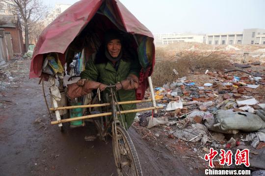 圖為老人走出窩棚，推著三輪車準備出去撿拾廢品。周小云 攝
