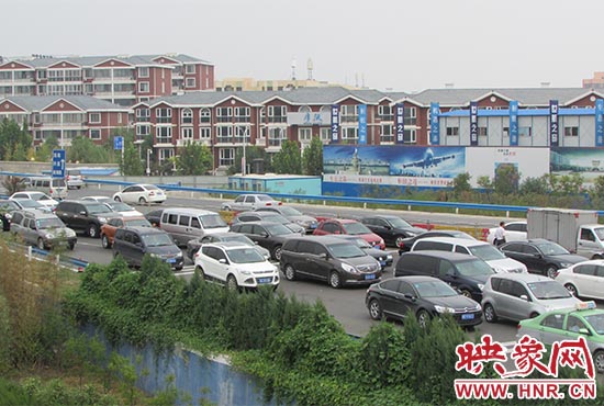 記者看到鄭州機(jī)場(chǎng)收費(fèi)站口車輛排隊(duì)，與此形成鮮明對(duì)比的是，路的對(duì)面（另一半幅）卻車輛較少，通行順暢。
