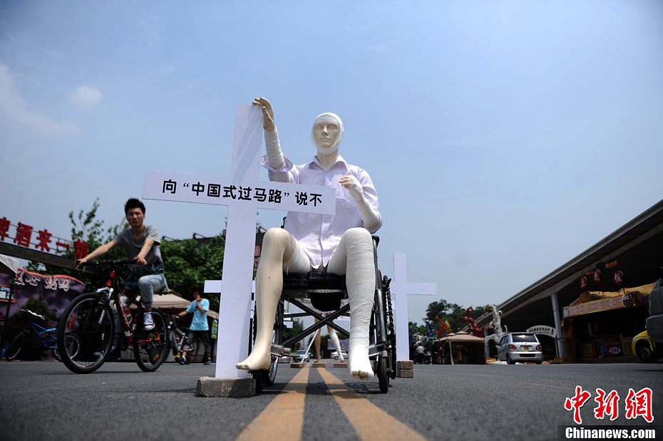 4月16日，重慶市洋人街上擺放著兩個(gè)受了傷的塑料人像“模特”，旁邊十字架上寫著向“中國式過馬路”說不