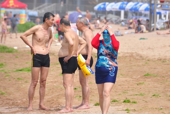 2013年7月3日，山東青島青島高溫來襲，“青島大媽”不懼滸苔，戴著“強盜面具”出現在海水浴場消暑降