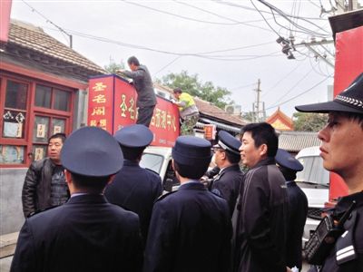 昨日下午,東城區(qū)工商、城管、公安等部門,對(duì)雍和宮附近的預(yù)測(cè)中心進(jìn)行清理整頓,站在車頂?shù)膬擅と苏鸪患摇邦A(yù)測(cè)中心”的招牌。因雍和宮、白云觀等文化景點(diǎn)外聚集大量算命先生,被媒體稱為“算命一條街”。本版攝影/新京報(bào)記者 李寧 攝