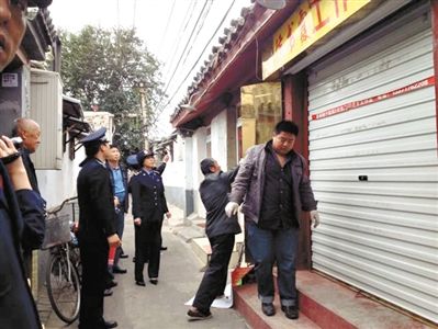 執(zhí)法人員拆除胡同里一家店面未經(jīng)審批的招牌。