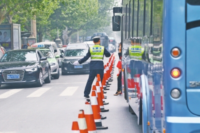 省人民醫(yī)院南門的路中間擺放反光錐，交警示意由西向東車輛從前方繞行。