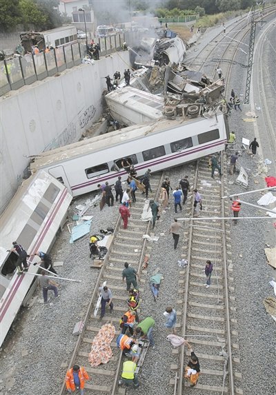 24日，救援人員在西班牙列車脫軌現(xiàn)場。一節(jié)車廂被強大的慣性拋上鐵道邊的高臺。