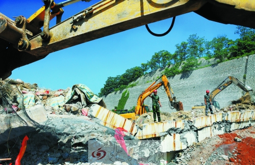 為確保道路盡早通車，工人師傅冒著烈日，指揮施工機械清理爆破現(xiàn)場