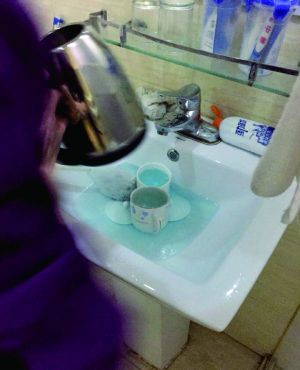 酒店服務(wù)員用潔廁液刷燒水壺和茶杯。