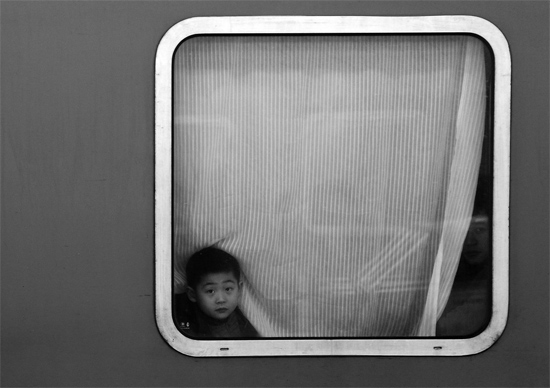 一個(gè)孩子把頭伸向窗外，他想再看送別的親人一眼