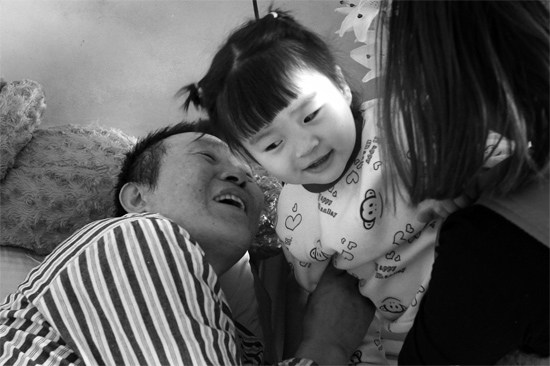 病床前李剛父女倆說著“悄悄話”，幸福的氣氛洋溢在病房中