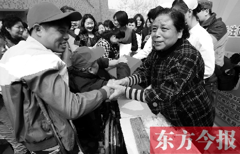 昨日，鄭大四附院的大樓前，“面人鄭”鄭玉芬（右）向前來捐款的殘疾人表示感謝