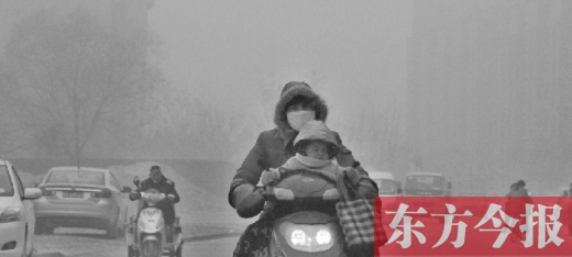 12月8日，鄭州市未來路上，一位市民帶著孩子在霧中騎行
