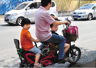 周先生騎著一輛低矮的電動(dòng)車帶著一對(duì)兒女，很不安全。