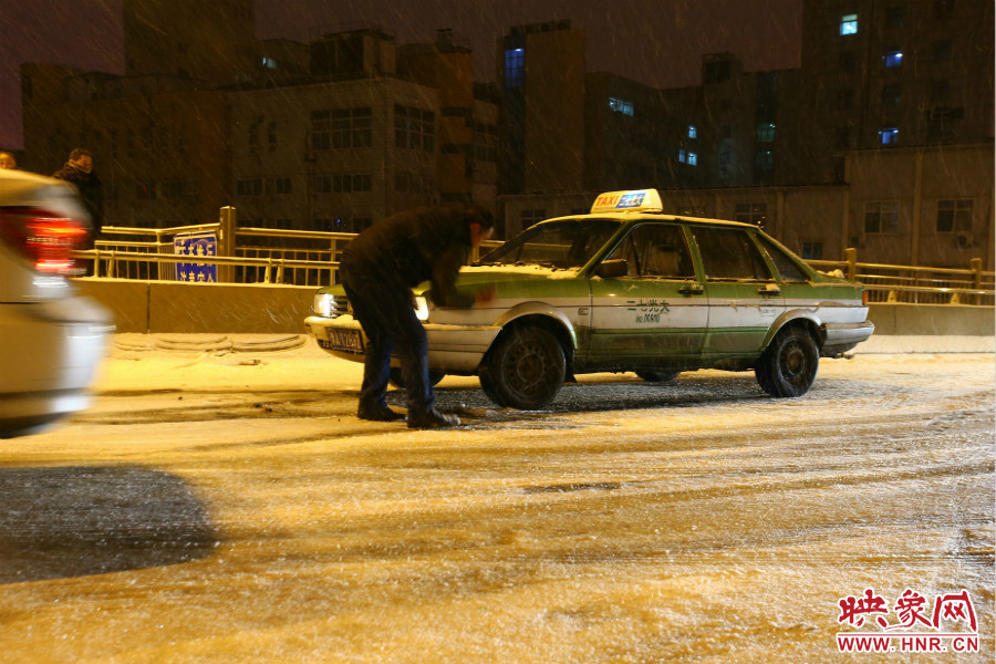 一位出租車司機(jī)在車輪前灑上雪，希望能增加輪胎的摩擦力。