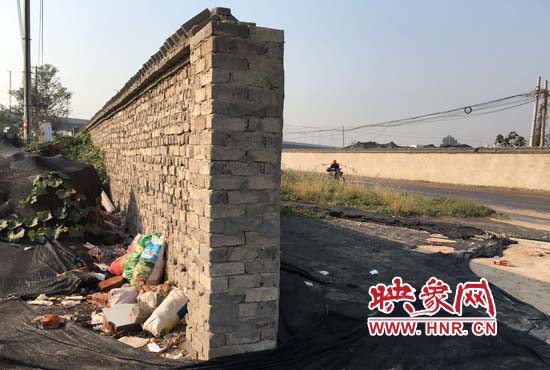 一墻之隔，一邊是道路，一邊是垃圾和荒草，市民質(zhì)疑其為遮羞墻。