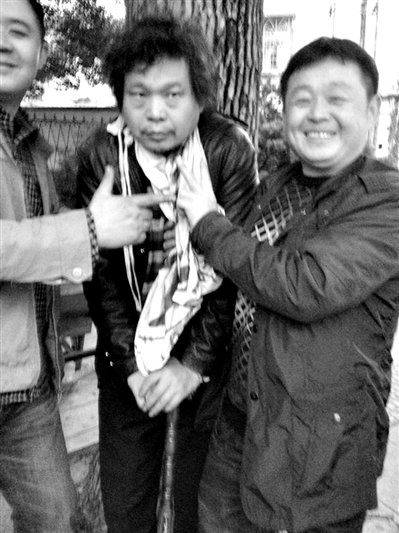 兩名接訪人員與患有癌癥的訪民段新德合影時，面帶笑容擺出勝利的手勢。