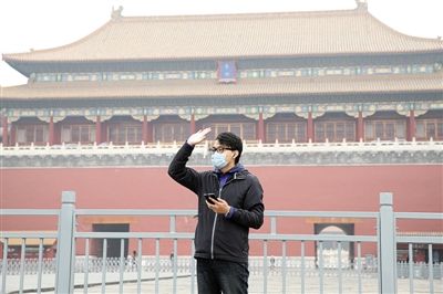 11月1日，北京大部分地區(qū)重度污染，一名游客戴著口罩在午門前揮手跟朋友打招呼。 實(shí)習(xí)生 王飛 攝