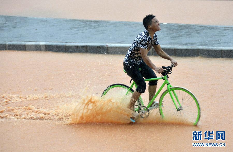 5月11日，一名行人在深圳街頭冒雨騎行。
