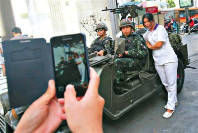 20日，泰國首都曼谷，一名婦女與執(zhí)行軍管任務的士兵合影。