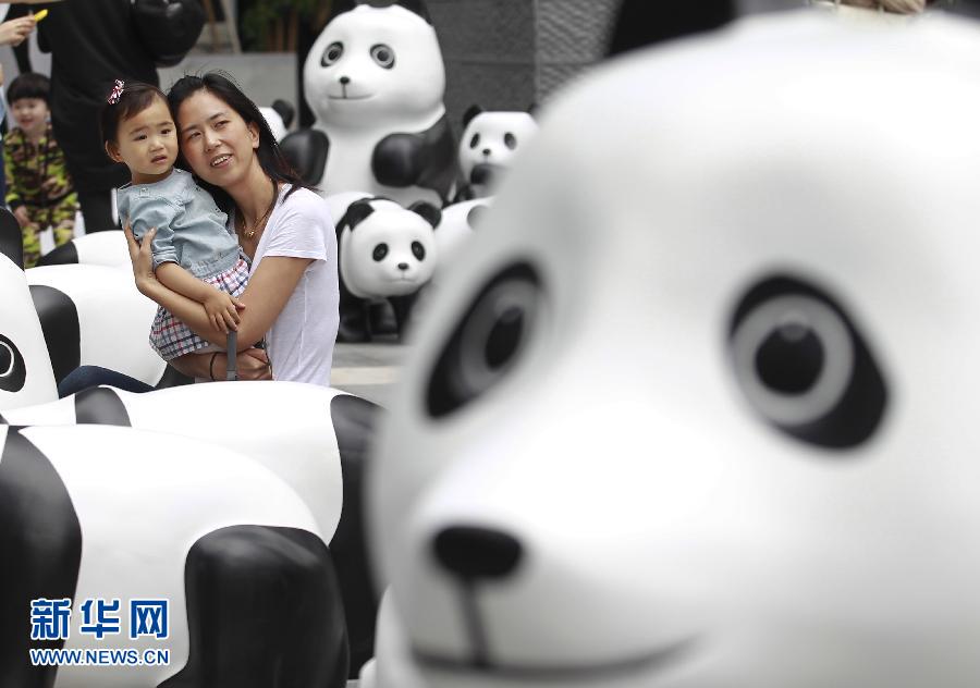 6月2日，一位家長(zhǎng)帶著孩子在上海街頭和大熊貓模型合影。