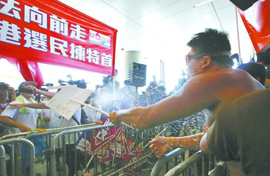 17日，在香港立法會(huì)外，一名反對(duì)政改的男子向支持派人群投擲標(biāo)牌。