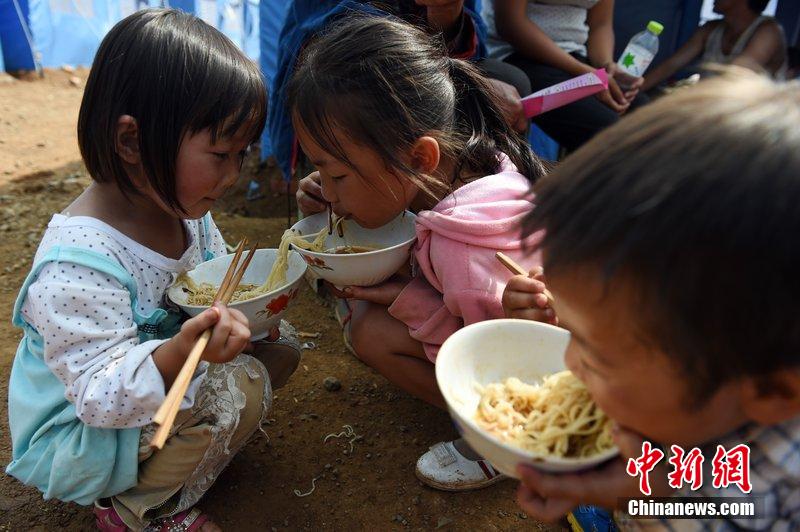 2014年8月6日，云南魯?shù)辇堫^山災(zāi)區(qū)，兒童在帳篷外吃飯。