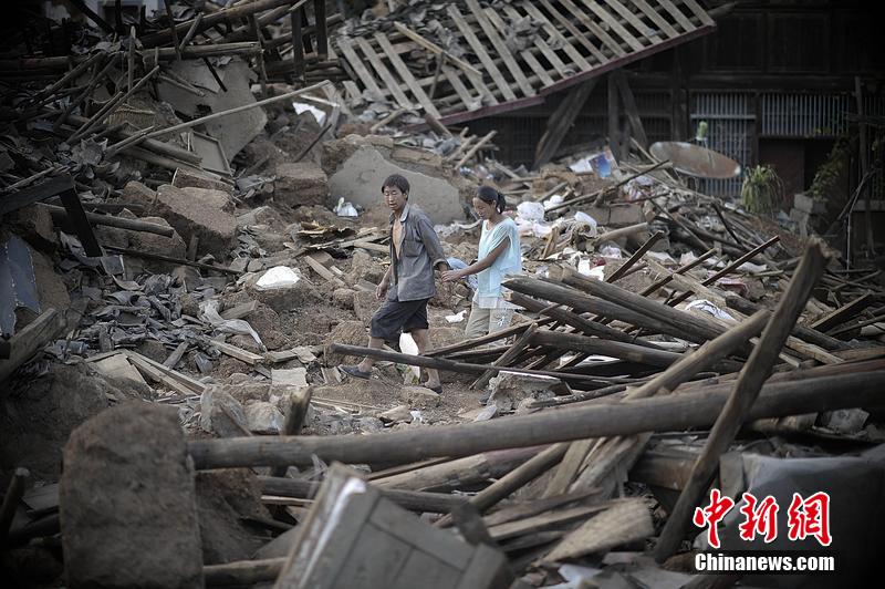 2014年8月5日，云南昭通龍頭山鎮(zhèn)老街，一對(duì)夫妻從居住房屋的廢墟中走過(guò)。