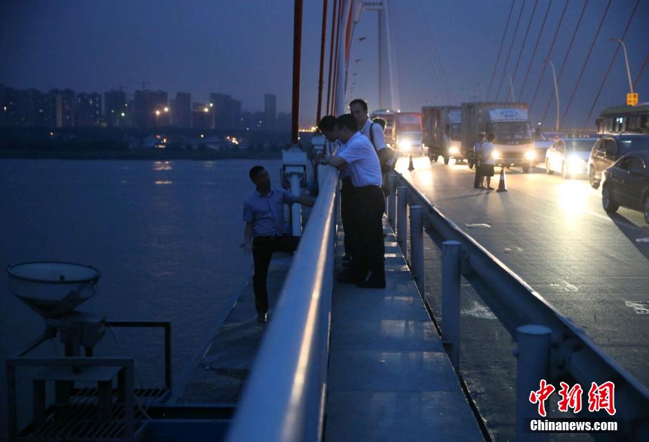 圖為武漢警方談判專家正在與翻爬至大橋外側(cè)護欄的劫持者談判。