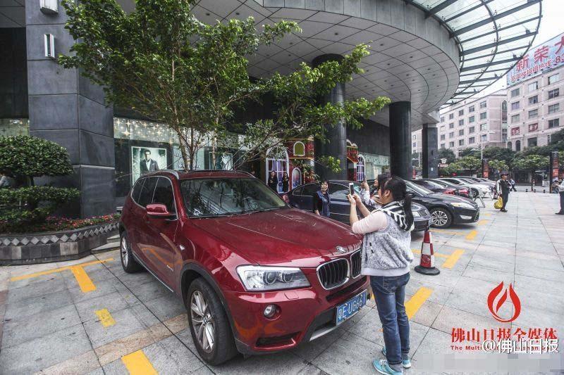 一輛停在停車位上的寶馬轎車，被墜落的樹枝砸中，樹枝徑直插入車內(nèi)，現(xiàn)場引發(fā)不少市民圍觀拍照。