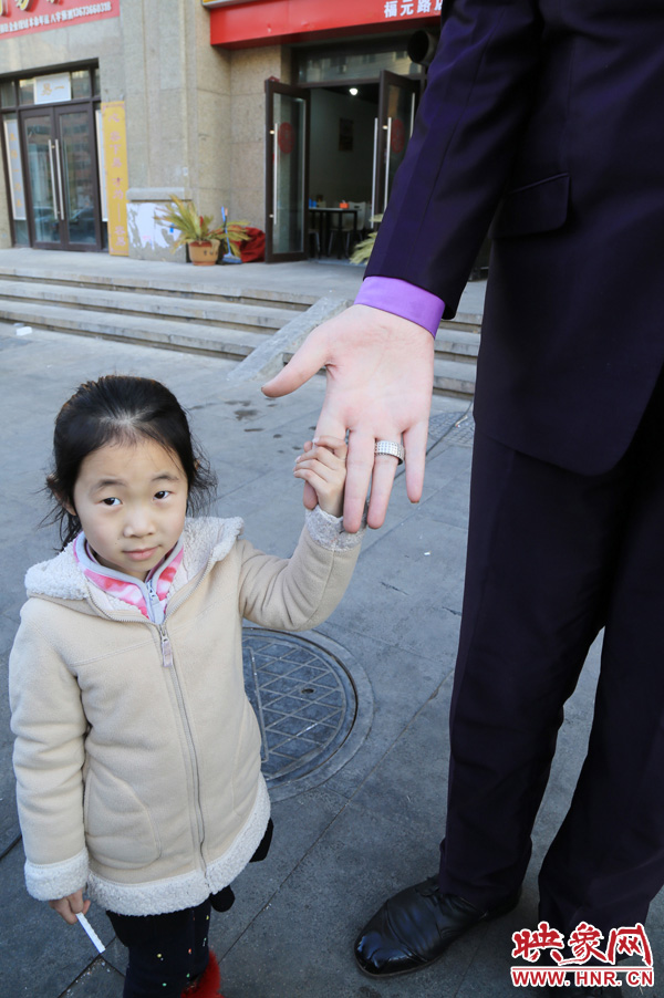 巨人“張歡”牽著一名漂亮的小女孩，兩人的手大小對(duì)比非常明顯。