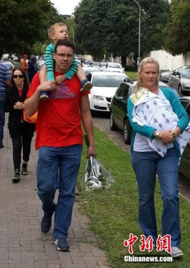 圖為一個(gè)白人家庭，由父母帶著孩子到曼德拉家門外悼念。中新社發(fā) 宋方燦 攝