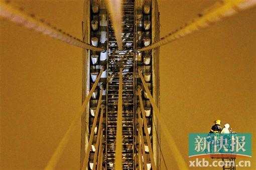 截至今日零時(shí)，男子仍未有下橋舉動(dòng)。圖為公安和消防人員乘消防云梯在高空上和男子交談。